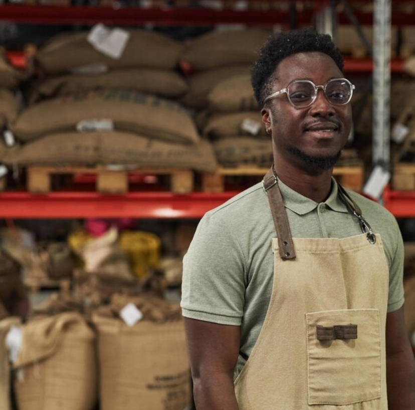 black-man-wearing-apron-smiling-camera-warehouse-coffee-roastery_236854-56150
